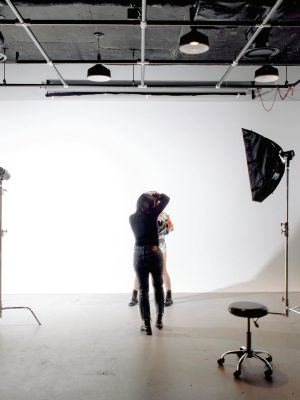 Back view of unrecognizable professional photographer taking photo of anonymous model in modern light studio