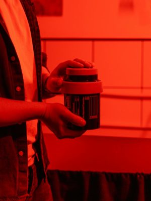 Man in White Button Up Shirt Holding Black and Red Labeled Can